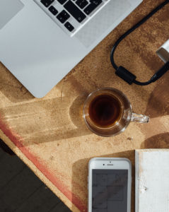 Laptop, smart phone and coffee on rough work bench.