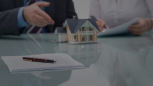 Two people discuss and point towards house design sitting on desk.